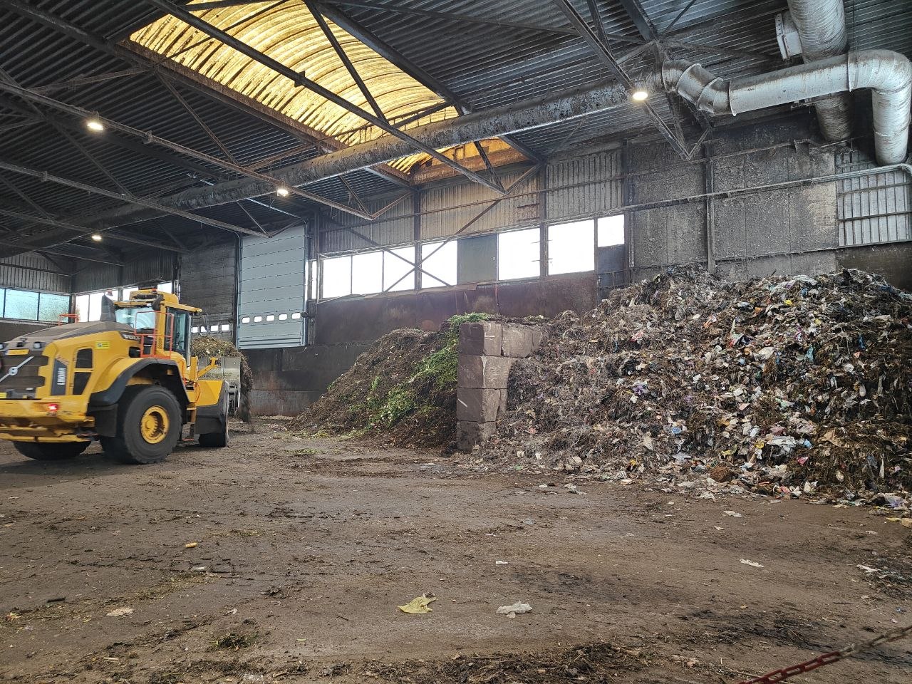 wheel loader next to heaps of organic waste in a processing hall